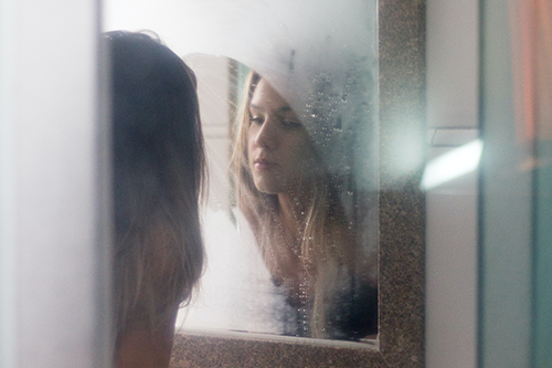 A girl looking at herself in a foggy mirror