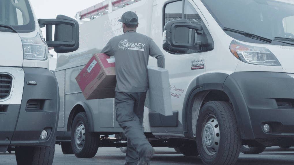 Legacy Heating and Air technician carrying two boxes.